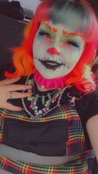 a woman with colorful clown makeup in a car