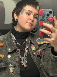 a woman taking a selfie in a mirror wearing a denim jacket