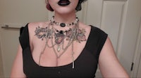 a woman with tattoos and black makeup is posing in front of a mirror